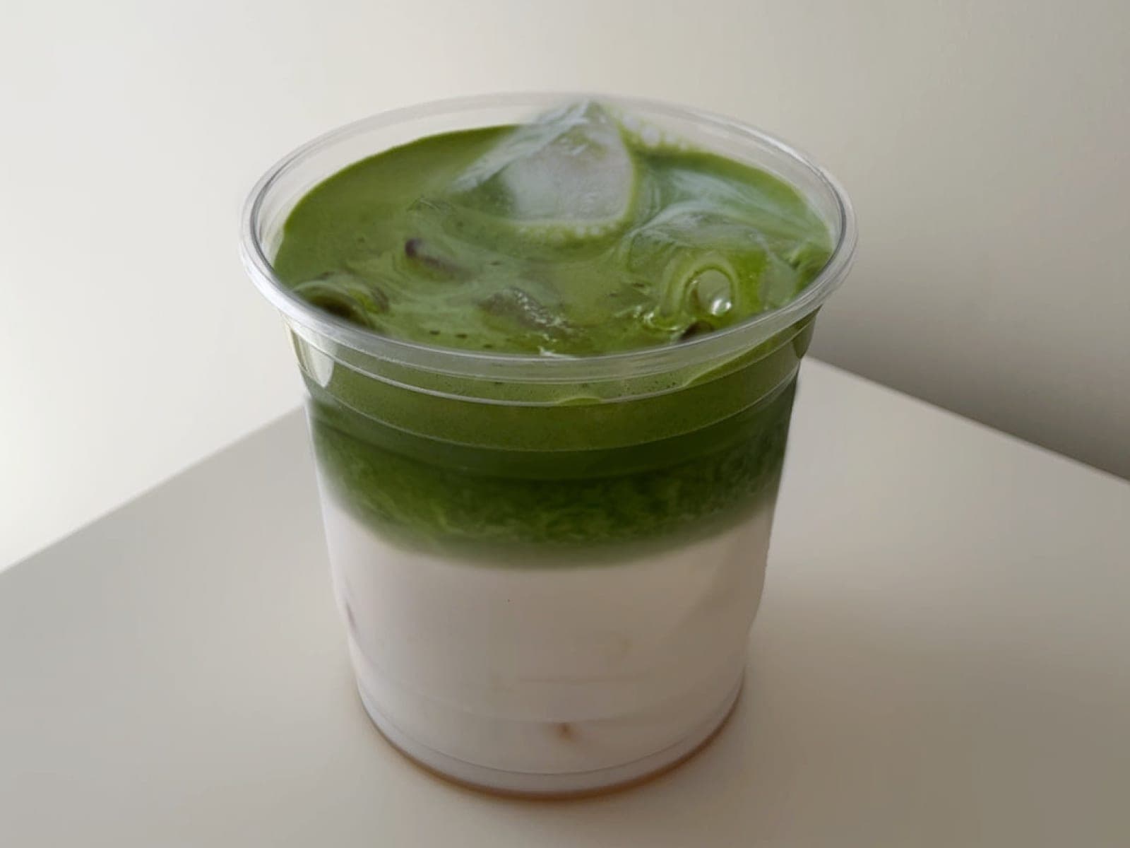 Iced matcha latte layered over silky pudding in a clear cup